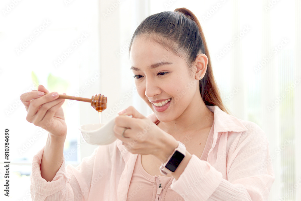 Beautiful happy smiling Asian woman looking at good honey source of sweetness for healthy food and beverage drink. Sporty girl making healthy diet from sweet honey to lose weight, get slim and healthy Beautiful happy smiling Asian woman looking at good honey source of sweetness for healthy food and beverage drink. Sporty girl making healthy diet from sweet honey to lose weight, get slim and healthy