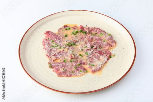 Thinly sliced pieces of beef with sauce. Beef carpaccio. Traditionally served as a cold dish or snack. Copy space. Isolated object.