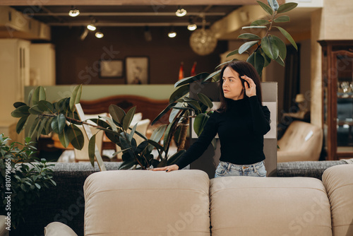 Young woman choosing sofa and pillow in furniture store photo