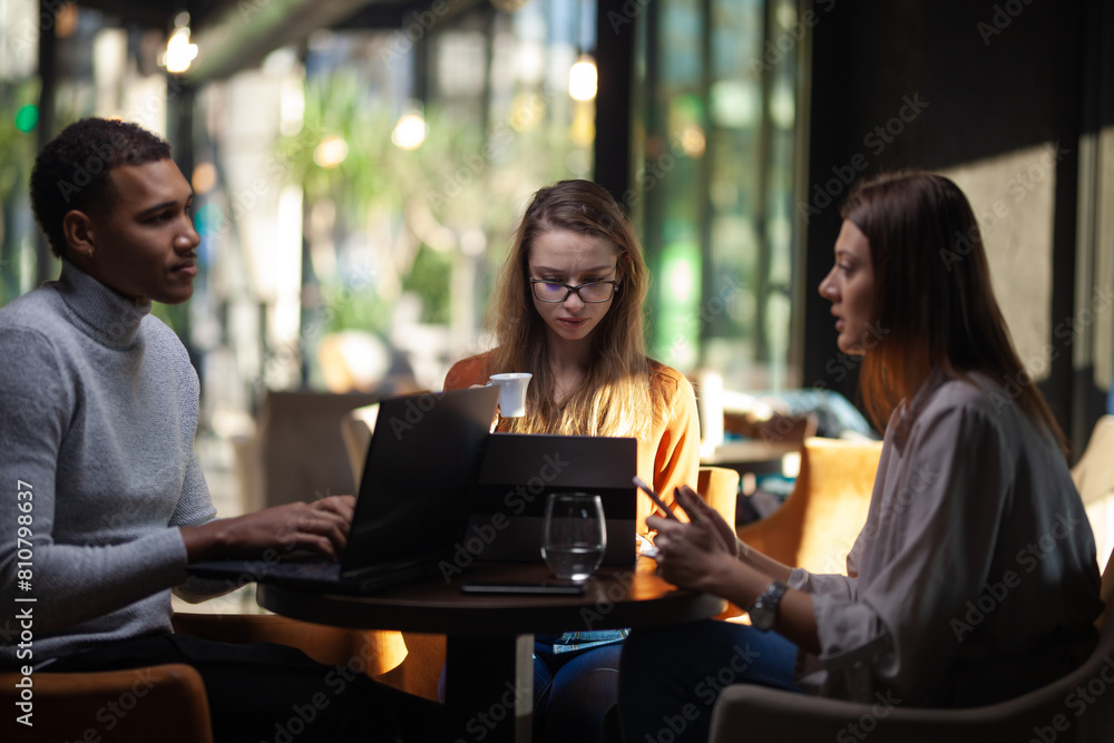 Three multiracial business colleagues having a meeting after work or during coffee break in a restaurant. Friends working at a cafe bar.. Three multiracial business colleagues having a meeting after work or during coffee break in a restaurant. Friends working at a cafe bar..