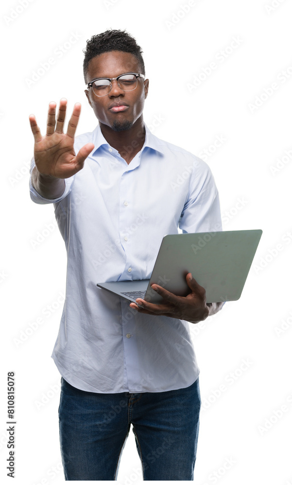 Young african american businessman using computer laptop with open hand doing stop sign with serious and confident expression, defense gesture Young african american businessman using computer laptop with open hand doing stop sign with serious and confident expression, defense gesture