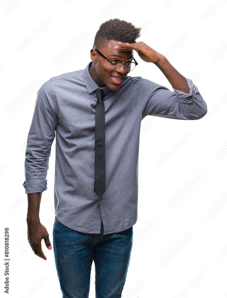 Fototapeta premium Young african american business man over isolated background very happy and smiling looking far away with hand over head. Searching concept.