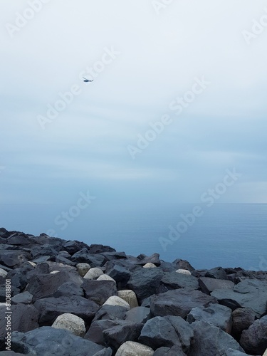 Helicopter flies on a rocky seashore