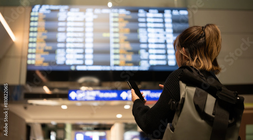 Bild auf Leinwand Young Asian woman in international airport looking at flight information board,