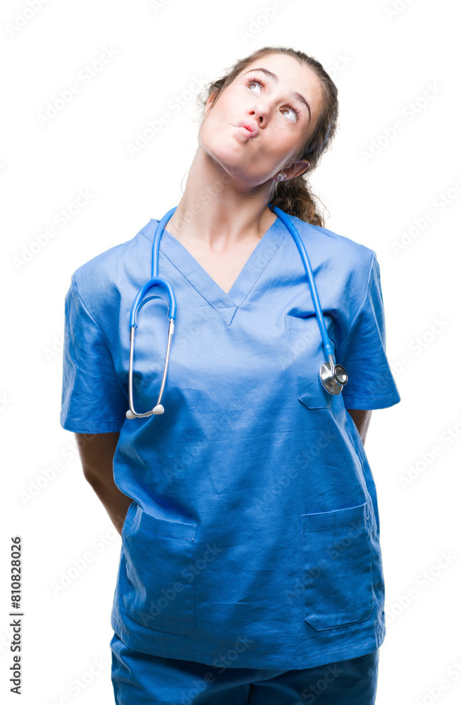 Young brunette doctor girl wearing nurse or surgeon uniform over isolated background making fish face with lips, crazy and comical gesture. Funny expression. Young brunette doctor girl wearing nurse or surgeon uniform over isolated background making fish face with lips, crazy and comical gesture. Funny expression.