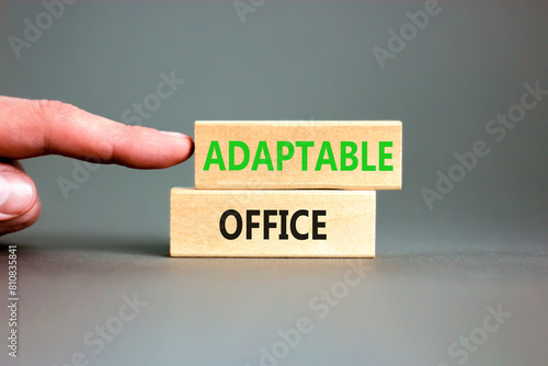 Adaptable office symbol. Concept words Adaptable office on beautiful wooden block. Beautiful grey paper background. Businessman hand. Business Adaptable office concept. Copy space.