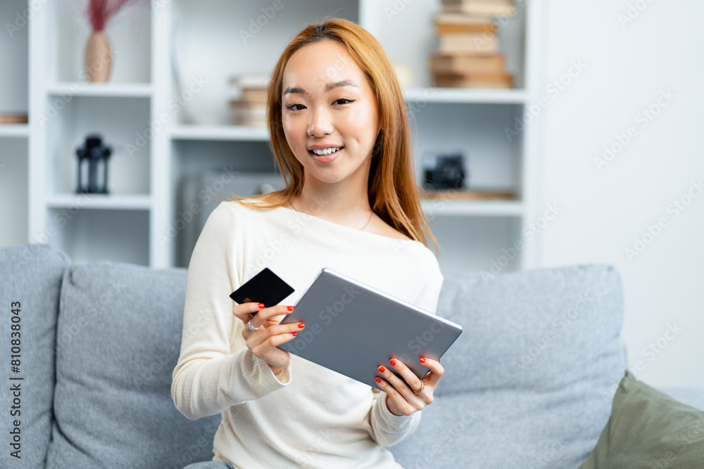 Happy Young Woman Using Tablet And Holding Credit Card On Couch, Online Shopping, Modern Lifestyle Happy Young Woman Using Tablet And Holding Credit Card On Couch, Online Shopping, Modern Lifestyle