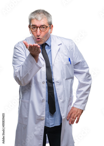Handsome senior doctor, scientist professional man wearing white coat over isolated background looking at the camera blowing a kiss with hand on air being lovely and sexy. Love expression. © Krakenimages.com