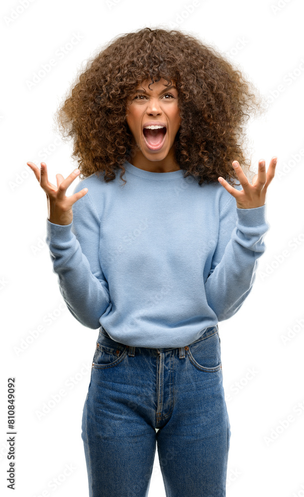 African american woman wearing a sweater crazy and mad shouting and yelling with aggressive expression and arms raised. Frustration concept. African american woman wearing a sweater crazy and mad shouting and yelling with aggressive expression and arms raised. Frustration concept.