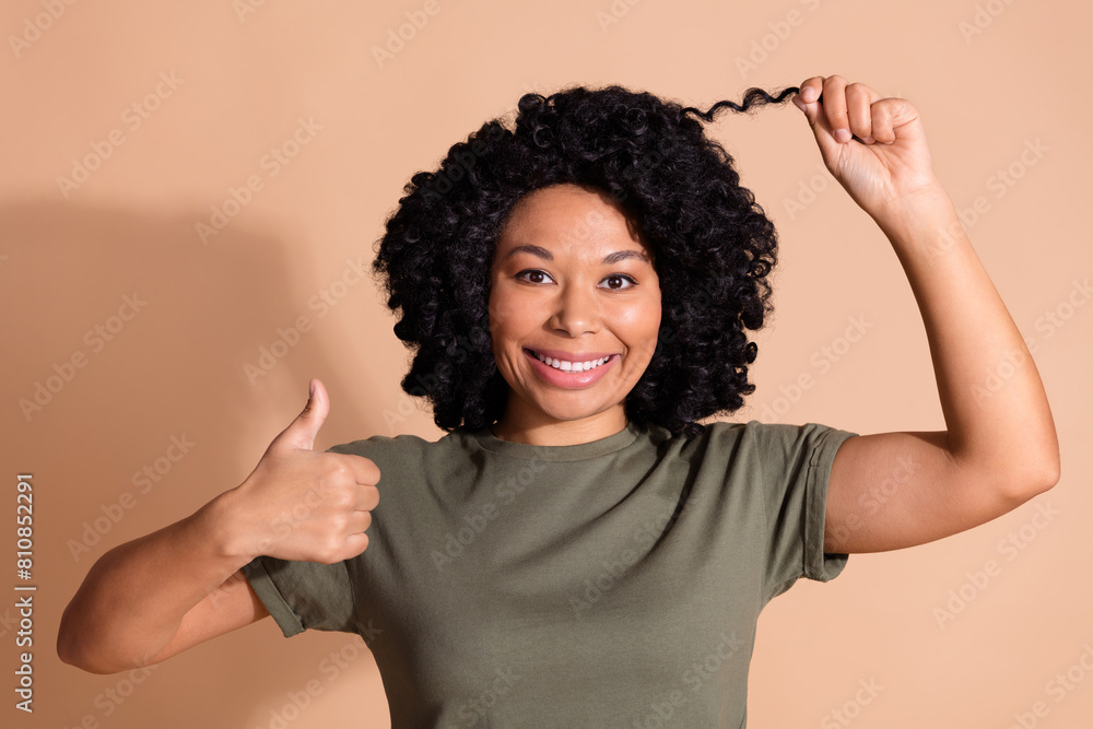 Portrait of positive person with perming coiffure dressed khaki t-shirt hold curl show thumb up isolated on pastel color background Portrait of positive person with perming coiffure dressed khaki t-shirt hold curl show thumb up isolated on pastel color background