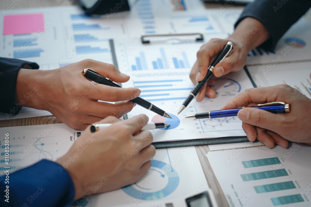 Naklejka premium A professional business team meeting in formal suits, working at desks with financial papers, calculators, and laptops. Close-up of hands. Discussion on revenue, brand, sales, agenda, capital