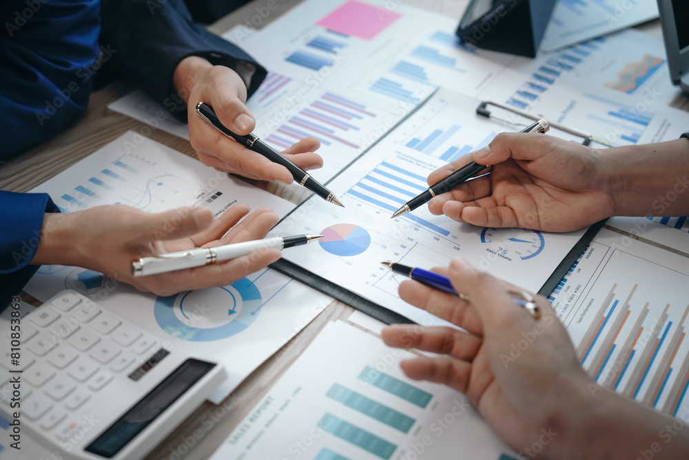 A professional business team meeting in formal suits, working at desks with financial papers, calculators, and laptops. Close-up of hands. Discussion on revenue, brand, sales, agenda, capital A professional business team meeting in formal suits, working at desks with financial papers, calculators, and laptops. Close-up of hands. Discussion on revenue, brand, sales, agenda, capital