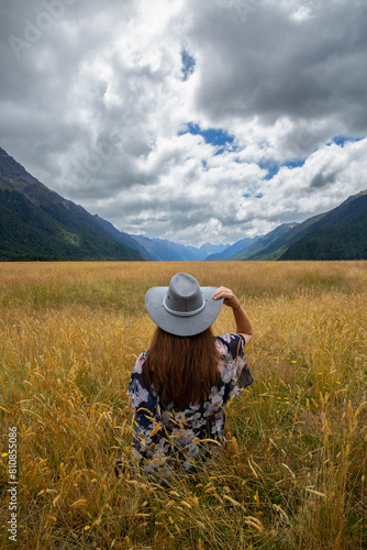 Wallpaper Mural Open plains and wild grasses looking accross to Milford Sound, model wears a grey cowboy hat looking away from camera into distance Torontodigital.ca