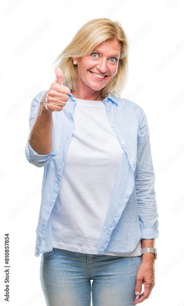 Middle age blonde woman over isolated background doing happy thumbs up gesture with hand. Approving expression looking at the camera with showing success. Middle age blonde woman over isolated background doing happy thumbs up gesture with hand. Approving expression looking at the camera with showing success.