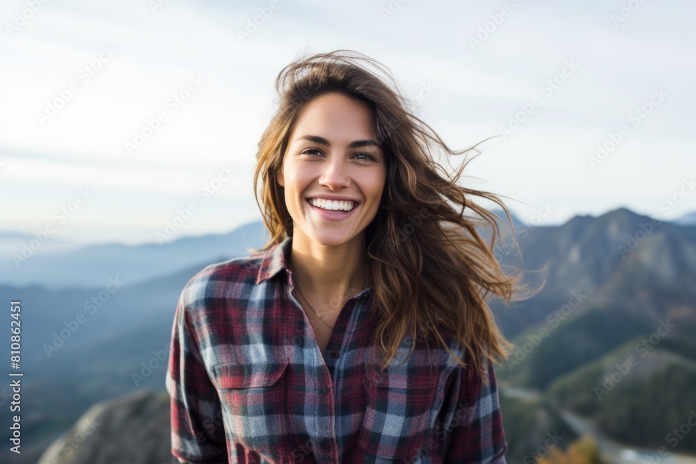 Portrait of a cheerful woman in her 30s wearing a comfy flannel shirt while standing against panoramic mountain vista Portrait of a cheerful woman in her 30s wearing a comfy flannel shirt while standing against panoramic mountain vista