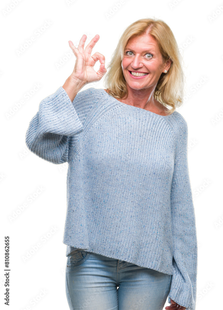 Middle age blonde woman wearing winter sweater over isolated background smiling positive doing ok sign with hand and fingers. Successful expression.