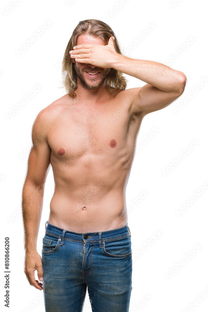 Fototapeta premium Young handsome shirtless man with long hair showing sexy body over isolated background smiling and laughing with hand on face covering eyes for surprise. Blind concept.