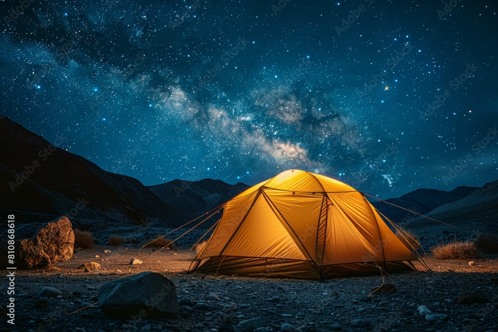 Majestic night scene with a brightly lit tent under a star-studded sky in a mountainous area