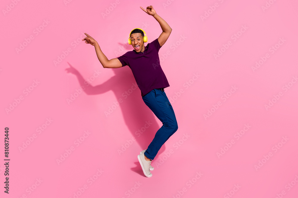 Full size photo of handsome young guy enjoy music dancing have fun wear trendy violet outfit isolated on pink color background Full size photo of handsome young guy enjoy music dancing have fun wear trendy violet outfit isolated on pink color background