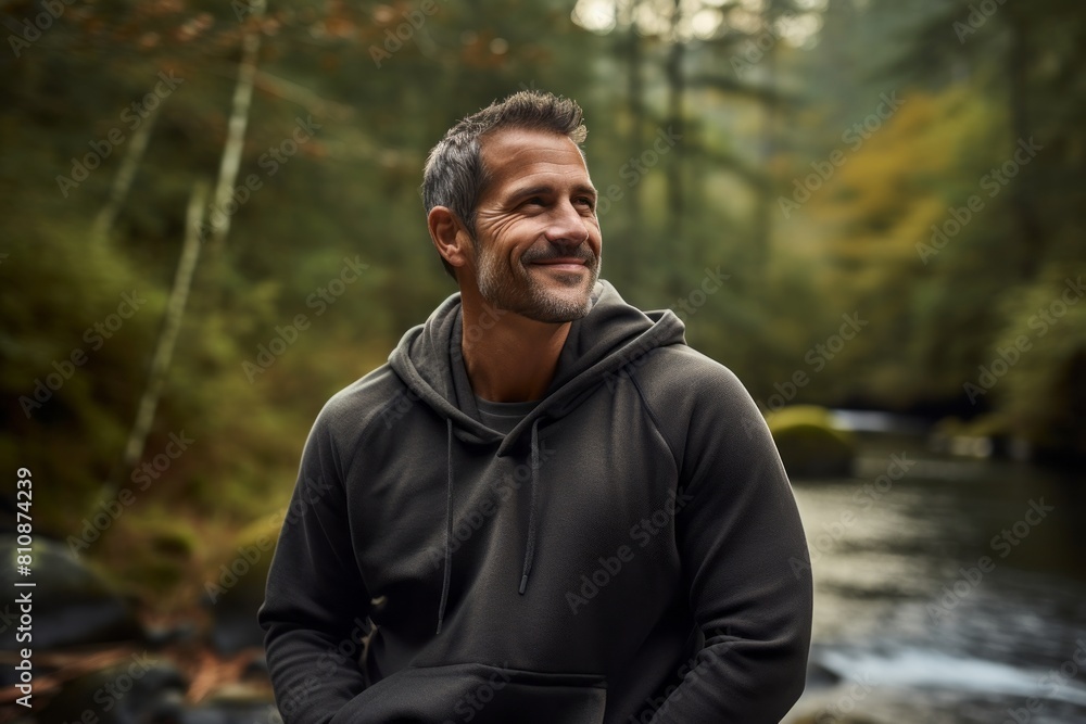 Portrait of a satisfied man in his 40s dressed in a comfy fleece pullover isolated on tranquil forest stream Portrait of a satisfied man in his 40s dressed in a comfy fleece pullover isolated on tranquil forest stream