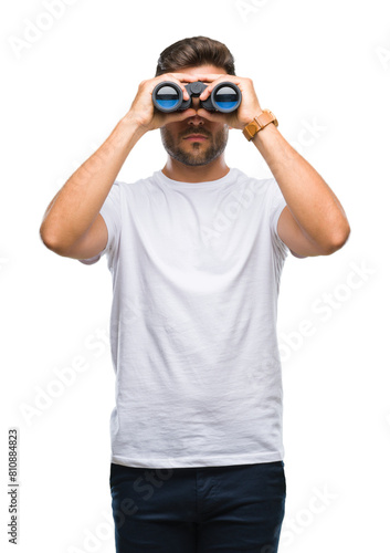 Cuadro en lienzo Young handsome man looking through binoculars over isolated background with a co