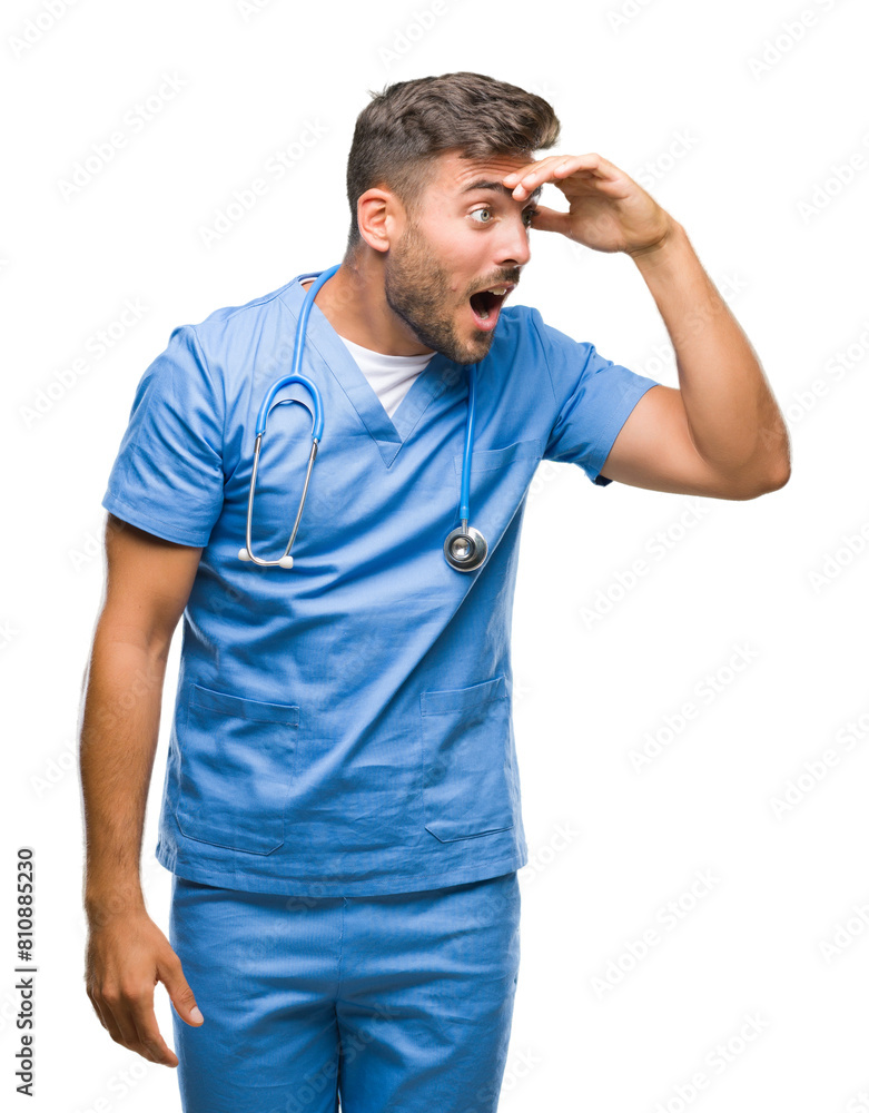 Fototapeta premium Young handsome doctor surgeon man over isolated background very happy and smiling looking far away with hand over head. Searching concept.