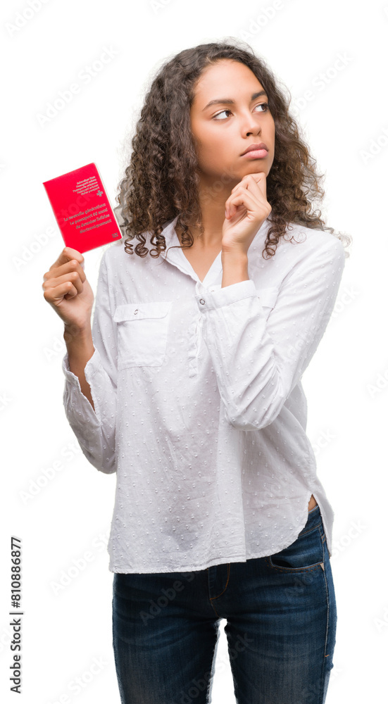 Young hispanic woman holding passport of Switzerland serious face thinking about question, very confused idea Young hispanic woman holding passport of Switzerland serious face thinking about question, very confused idea