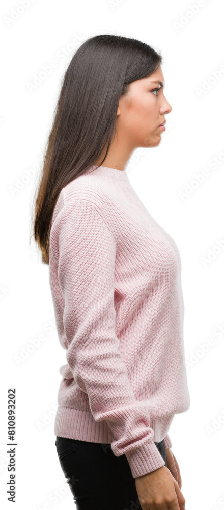 Young beautiful hispanic woman wearing a sweater looking to side, relax profile pose with natural face with confident smile. Young beautiful hispanic woman wearing a sweater looking to side, relax profile pose with natural face with confident smile.