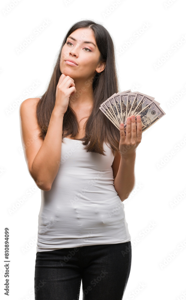 Young hispanic woman holding dollars serious face thinking about question, very confused idea Young hispanic woman holding dollars serious face thinking about question, very confused idea