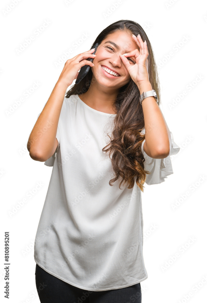 Young beautiful arab woman talking on the phone over isolated background with happy face smiling doing ok sign with hand on eye looking through fingers Young beautiful arab woman talking on the phone over isolated background with happy face smiling doing ok sign with hand on eye looking through fingers