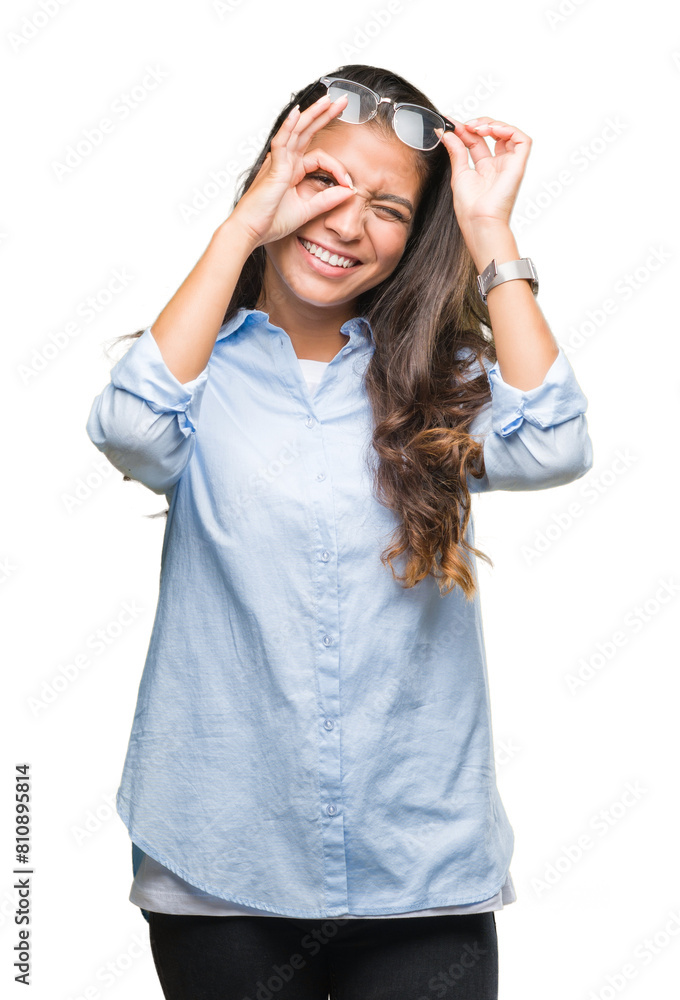 Young beautiful arab woman wearing glasses over isolated background doing ok gesture with hand smiling, eye looking through fingers with happy face. Young beautiful arab woman wearing glasses over isolated background doing ok gesture with hand smiling, eye looking through fingers with happy face.