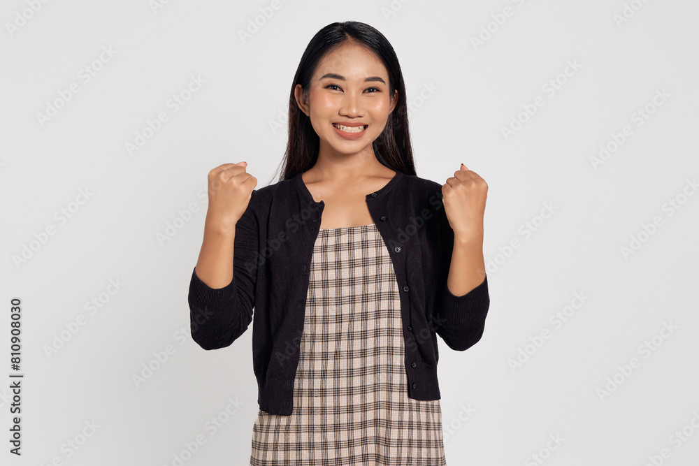 Big win. Excited young Asian woman wearing casual shirt making winner gesture with raised hands, celebrating successisolated on white background. People lifestyle concept