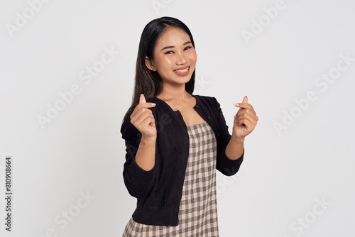 Cheerful beautiful young Asian woman wearing casual shirt showing hands fingers demonstrates korean love heart symbol isolated on white background. People lifestyle concept