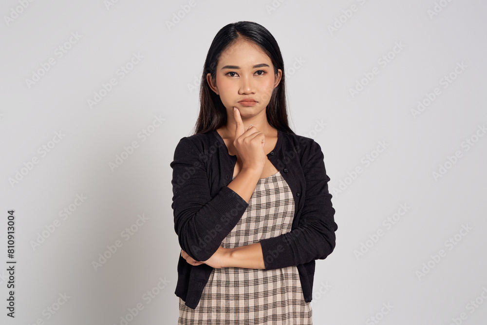 Beautiful young Asian woman wearing casual shirt holding his chin while looking at camera with pensive expression, thinking about advertising content future isolated on white background Beautiful young Asian woman wearing casual shirt holding his chin while looking at camera with pensive expression, thinking about advertising content future isolated on white background
