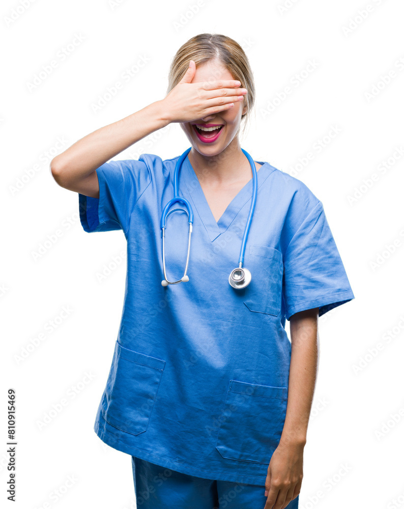 Young beautiful blonde doctor surgeon nurse woman over isolated background smiling and laughing with hand on face covering eyes for surprise. Blind concept. Young beautiful blonde doctor surgeon nurse woman over isolated background smiling and laughing with hand on face covering eyes for surprise. Blind concept.