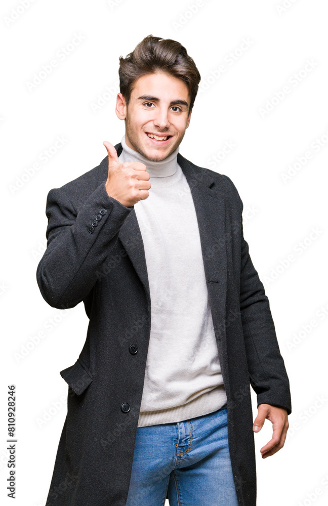 Young elegant man wearing winter coat over isolated background doing happy thumbs up gesture with hand. Approving expression looking at the camera showing success. Young elegant man wearing winter coat over isolated background doing happy thumbs up gesture with hand. Approving expression looking at the camera showing success.