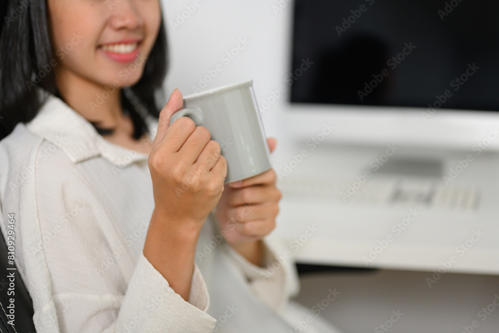 Smiling young businesswoman drinking coffee at the desk in the office Smiling young businesswoman drinking coffee at the desk in the office