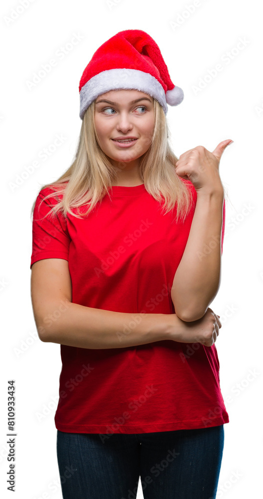 Young caucasian woman wearing christmas hat over isolated background smiling with happy face looking and pointing to the side with thumb up. Young caucasian woman wearing christmas hat over isolated background smiling with happy face looking and pointing to the side with thumb up.