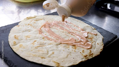 Flatbread wrap drizzled with sauce in slow motion