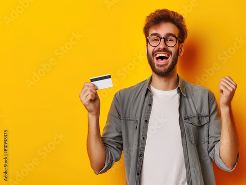 Enthusiastic about the rising trend of mobile payments, a young man proudly endorses contactless transactions, showcasing his credit card to the camera. photo