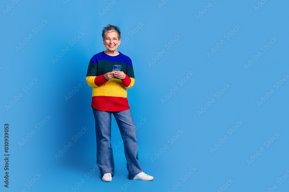 Photo of lovely positive nice senior woman wear stylish clothes empty space offer isolated on blue color background Photo of lovely positive nice senior woman wear stylish clothes empty space offer isolated on blue color background