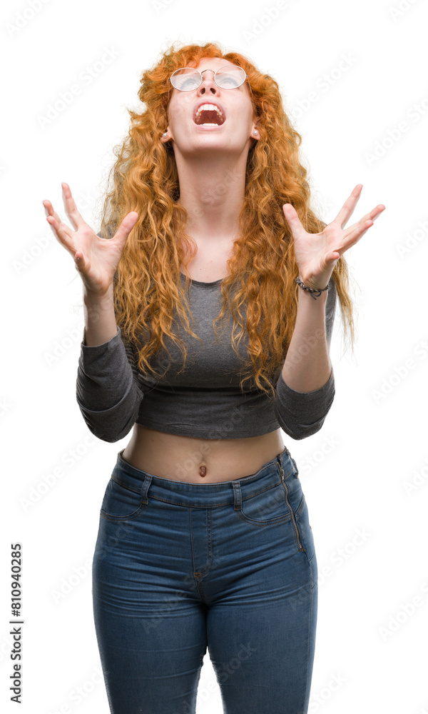 Young redhead woman crazy and mad shouting and yelling with aggressive expression and arms raised. Frustration concept. Young redhead woman crazy and mad shouting and yelling with aggressive expression and arms raised. Frustration concept.