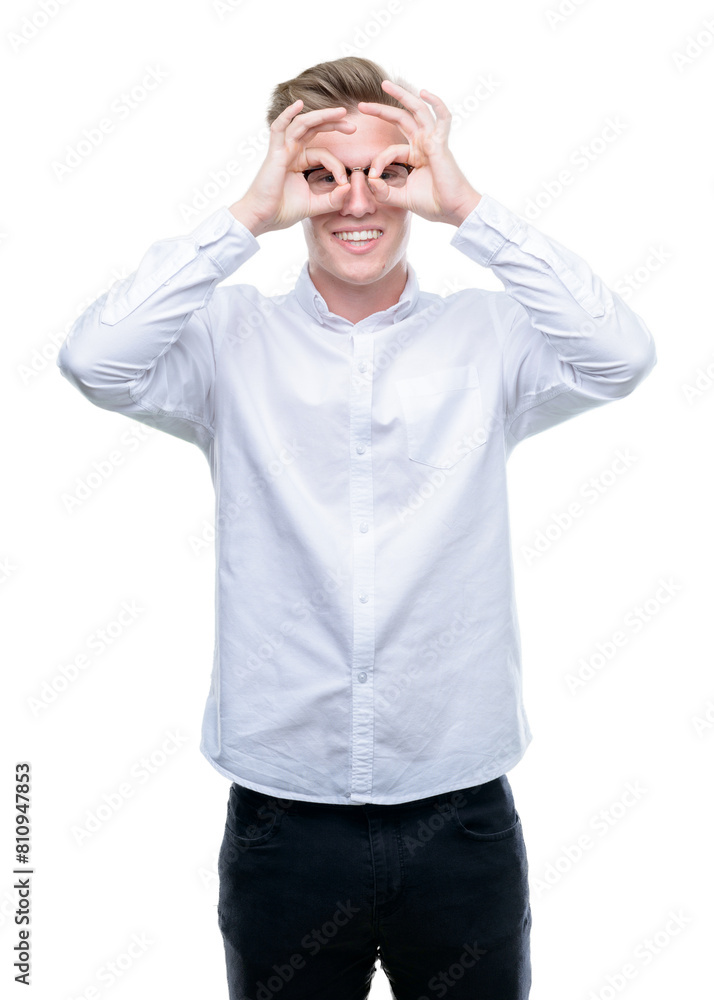 Young handsome blond man doing ok gesture like binoculars sticking tongue out, eyes looking through fingers. Crazy expression. Young handsome blond man doing ok gesture like binoculars sticking tongue out, eyes looking through fingers. Crazy expression.