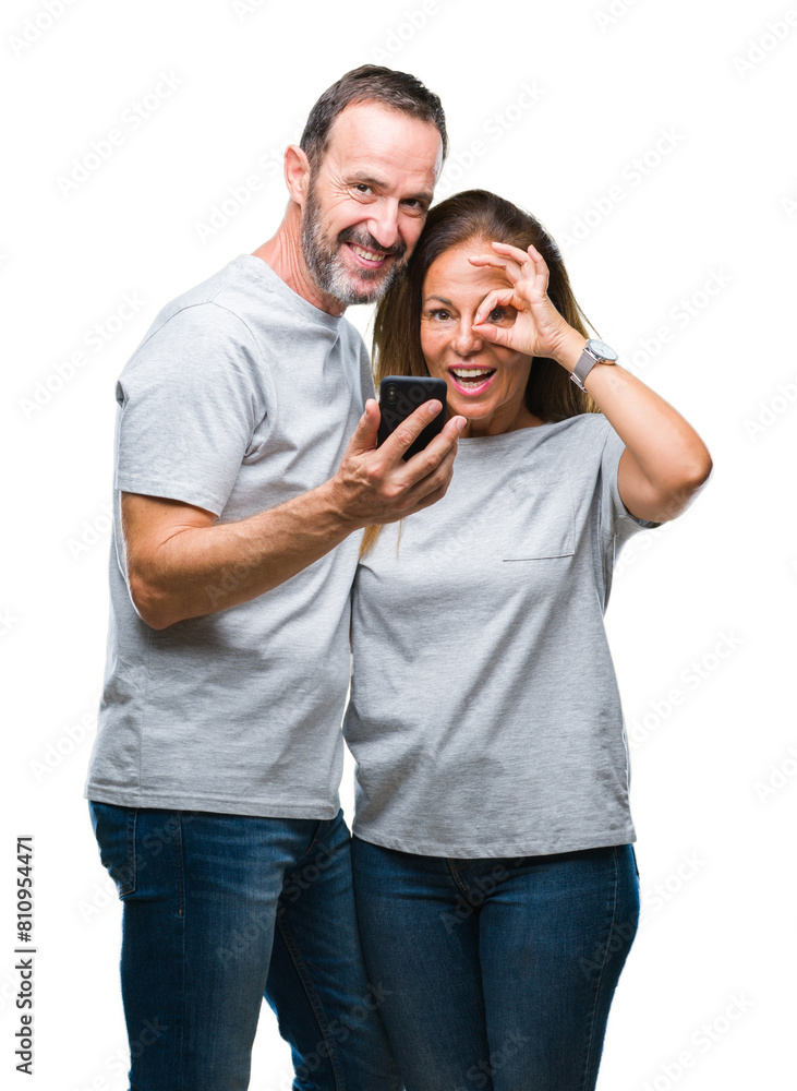Middle age hispanic couple texting message on smartphone ver isolated background with happy face smiling doing ok sign with hand on eye looking through fingers Middle age hispanic couple texting message on smartphone ver isolated background with happy face smiling doing ok sign with hand on eye looking through fingers