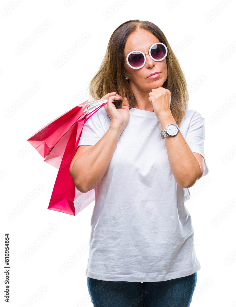 Middle age hispanic woman holding shopping bags on sales over isolated background serious face thinking about question, very confused idea Middle age hispanic woman holding shopping bags on sales over isolated background serious face thinking about question, very confused idea