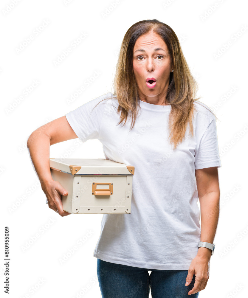 Middle age hispanic woman moving holding packing box over isolated background scared in shock with a surprise face, afraid and excited with fear expression Middle age hispanic woman moving holding packing box over isolated background scared in shock with a surprise face, afraid and excited with fear expression
