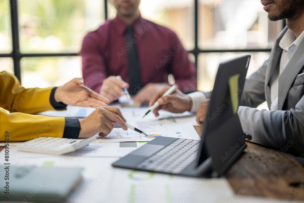 Three people are sitting at a table with a laptop and a tablet. They are working together on a project Three people are sitting at a table with a laptop and a tablet. They are working together on a project
