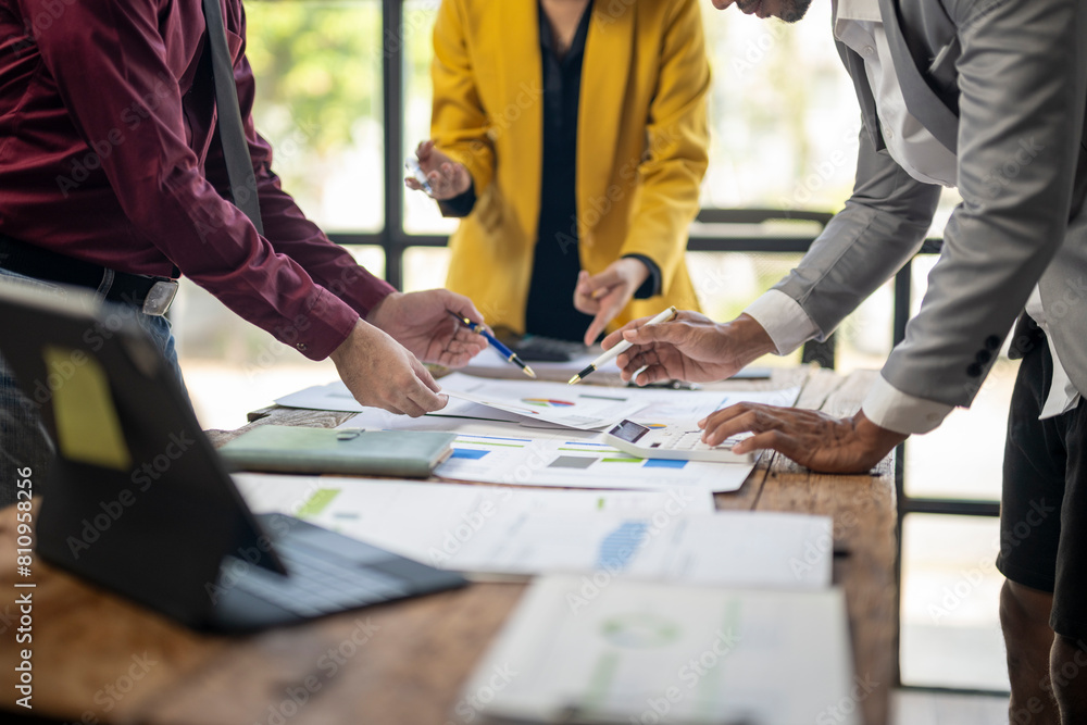 A group of people are working together at a table with papers and laptops. Scene is collaborative and focused A group of people are working together at a table with papers and laptops. Scene is collaborative and focused