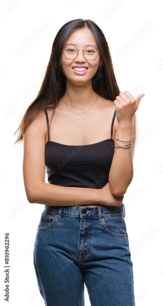 Young asian woman wearing glasses over isolated background smiling with happy face looking and pointing to the side with thumb up. Young asian woman wearing glasses over isolated background smiling with happy face looking and pointing to the side with thumb up.