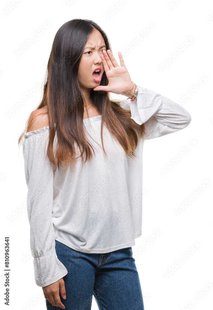 Young asian woman over isolated background shouting and screaming loud to side with hand on mouth. Communication concept.